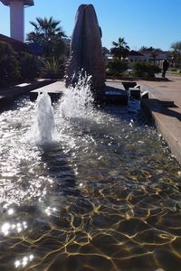 Water splashing in swimming pool against sky