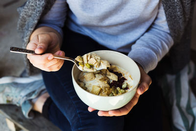 Midsection of woman holding bowl while sitting at home