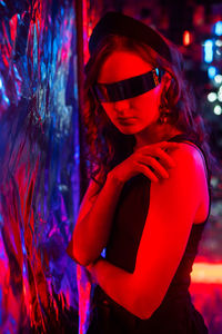 Young woman wearing sunglasses while standing against illuminated christmas tree