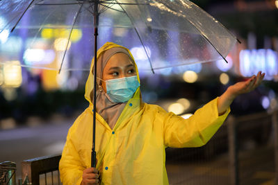 Portrait of woman with umbrella standing in rain