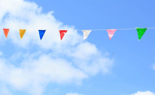 Low angle view of flags hanging against blue sky