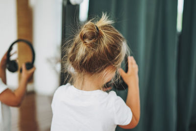 Cute happy toddler girl with fair hair in headphones having fun in bright interior