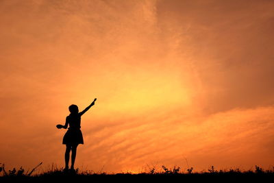 Silhouette of girl playing at sunset