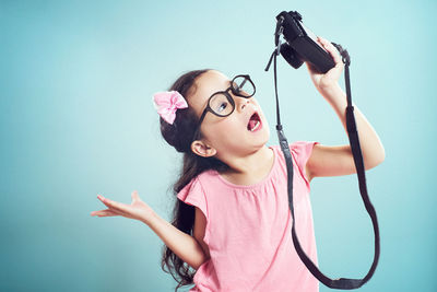 Girl taking selfie with camera while standing against turquoise background