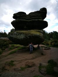 Rear view of woman standing on rock formation against sky