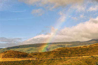 Scenic view of rainbow over land against sky