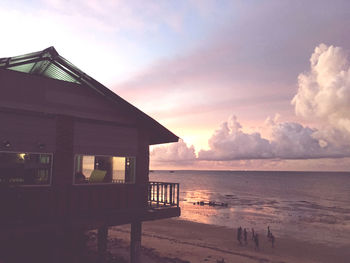 Building by sea against sky during sunset