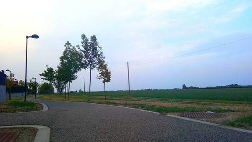 Road by trees against sky