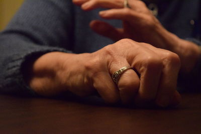 Close-up of person wearing finger ring on table at home