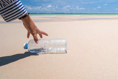 Midsection of person on sand at beach against sky