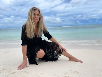 Portrait of woman crouching on sandy beach