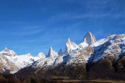 Scenic view of snowcapped mountains against blue sky