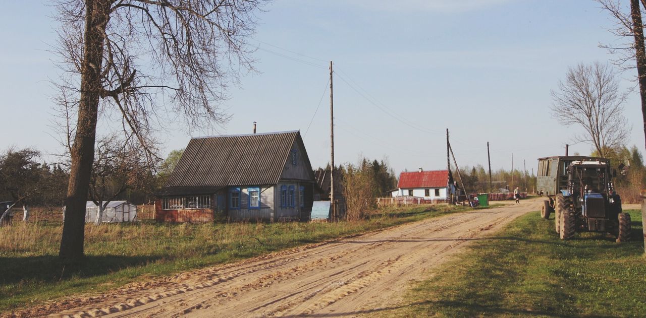 building exterior, architecture, built structure, house, tree, sky, residential structure, rural scene, field, village, residential building, clear sky, day, grass, barn, outdoors, bare tree, no people, landscape, dirt road