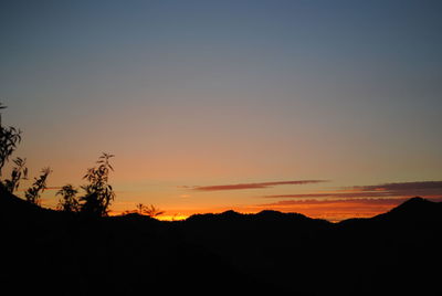 Scenic view of silhouette mountains against orange sky