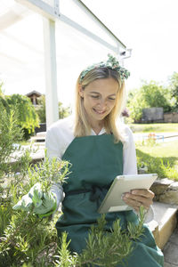 Portrait of smiling young woman standing against plants