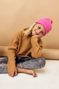 Portrait of a smiling young woman sitting against wall