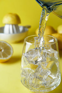 Pour water into a glass with ice to make lemon water