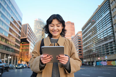 Portrait of young woman using digital tablet in city