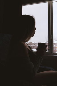 Woman sitting at beach seen through window