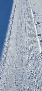 High angle view of tire tracks on snow covered land