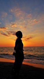 Silhouette man standing on beach against sky during sunset