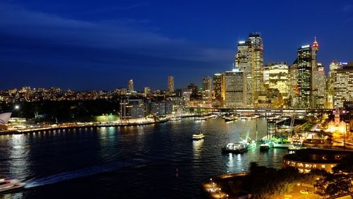 Illuminated modern buildings in city against sky at night