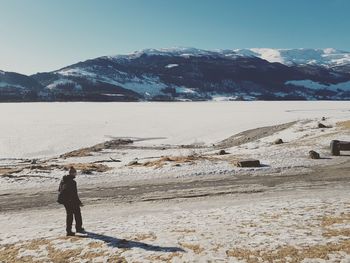 Man standing on snow covered mountain against sky