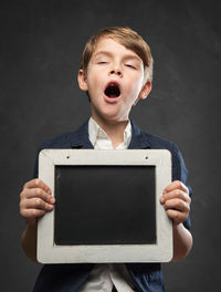 Close-up of boy standing against black background