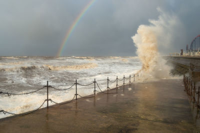 Scenic view of sea against rainbow in sky