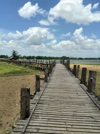 High angle view of boardwalk at beach against cloudy sky