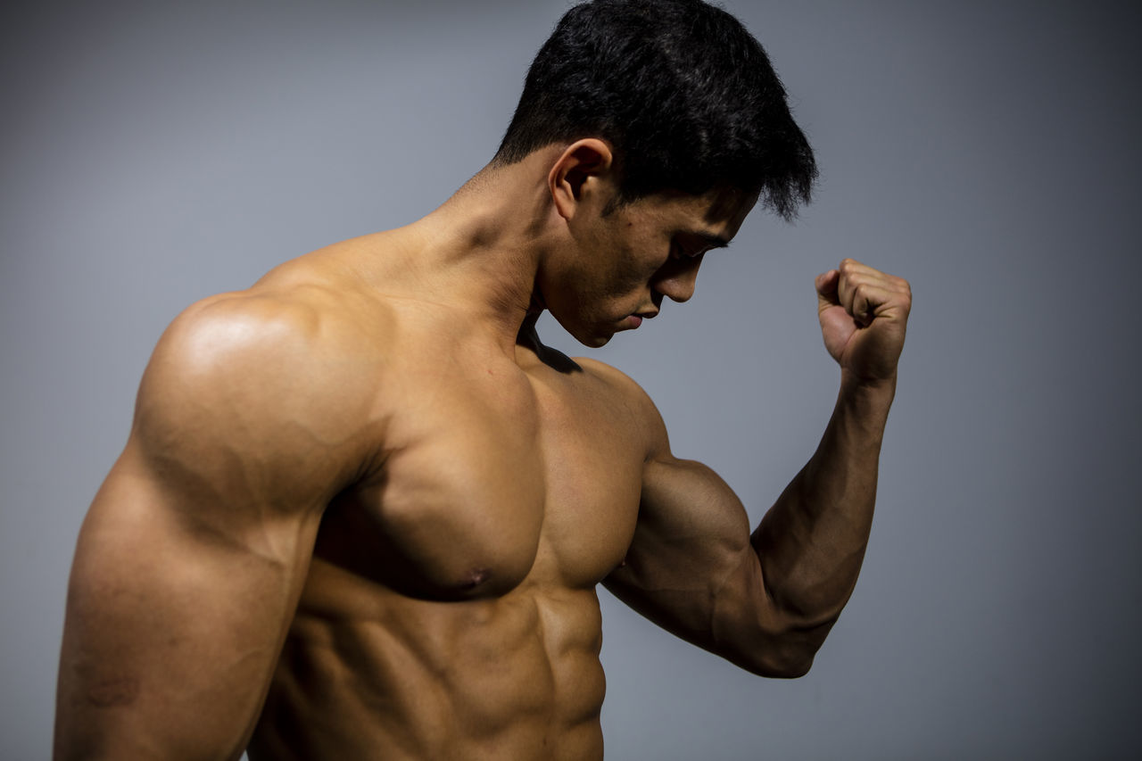 CLOSE-UP OF SHIRTLESS MAN LOOKING AT CAMERA OVER GRAY BACKGROUND