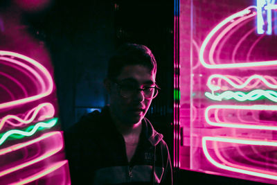 Full length portrait of young man against illuminated wall at night