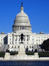 Statue against clear sky in front of the us capitol building in washington dc.