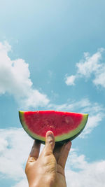 Midsection of person holding watermelon against sky
