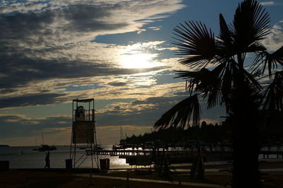 Silhouette palm trees on beach against sky during sunset