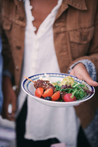 Midsection of woman holding meal in plate during social gathering on terrace