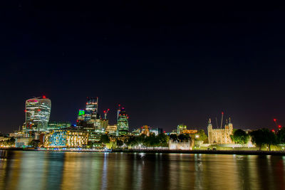 Illuminated buildings by the river thames against sky at night in london financial district
