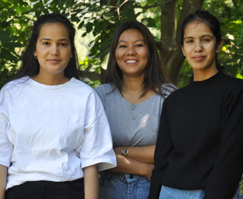 Front view of three indian young girls smiling with looking at camera and posing outdoors in nature 