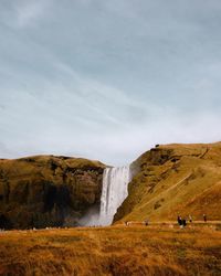 Scenic view of waterfall on land against sky