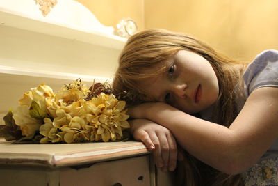 Close-up portrait of girl with yellow flowers at table