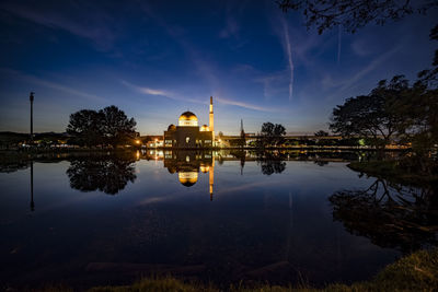 Reflection of illuminated buildings in lake against sky