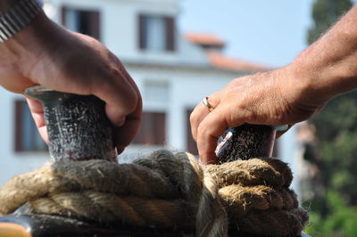 Close-up of human hands on moored rope