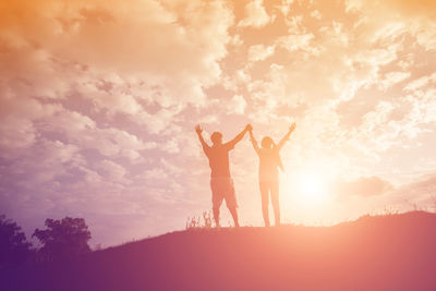 Silhouette couple standing against sky during sunset