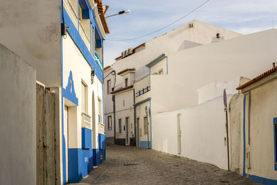 Empty alley amidst buildings against sky