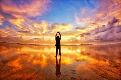 Silhouette man standing on beach against sky during sunset