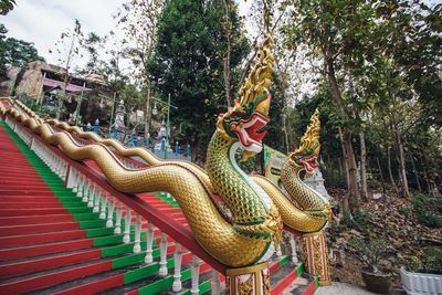 Statue of buddha against trees and building