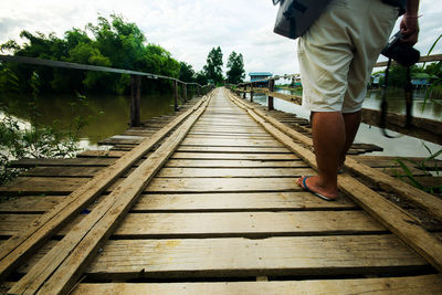 Low section of man standing on footbridge