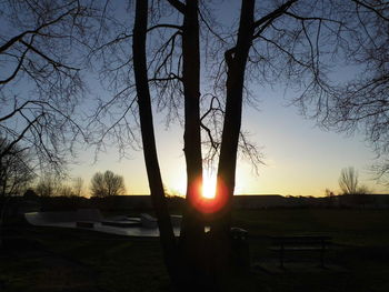 Silhouette trees on landscape against sky at sunset