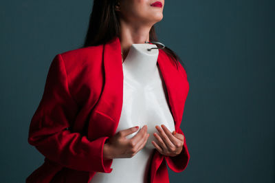 Midsection of woman with mannequin standing against wall