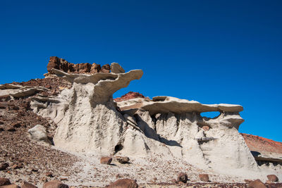 Low angle view of rock formation against clear blue sky